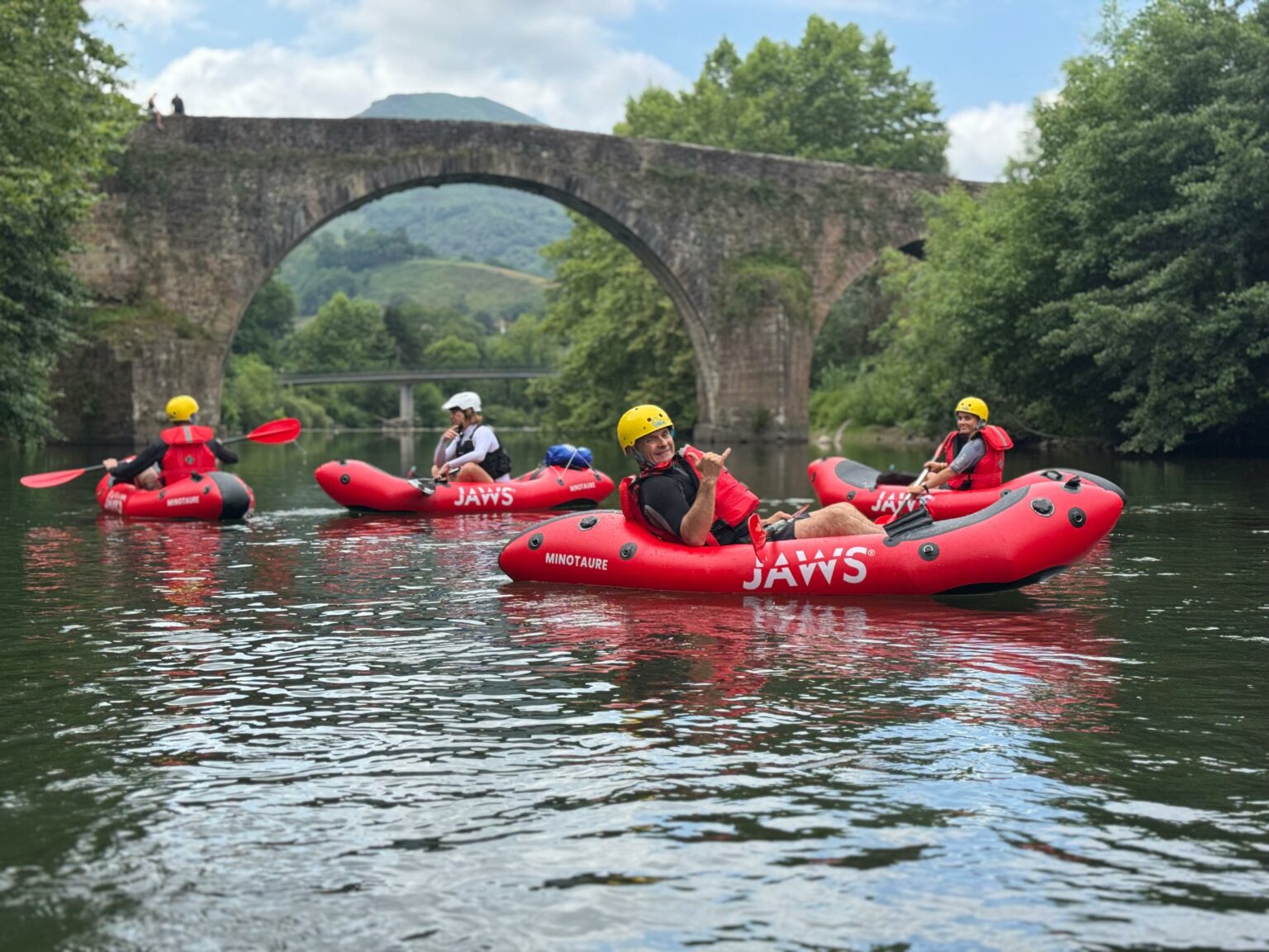Groupe en packraft sous un vieux pont de pierre