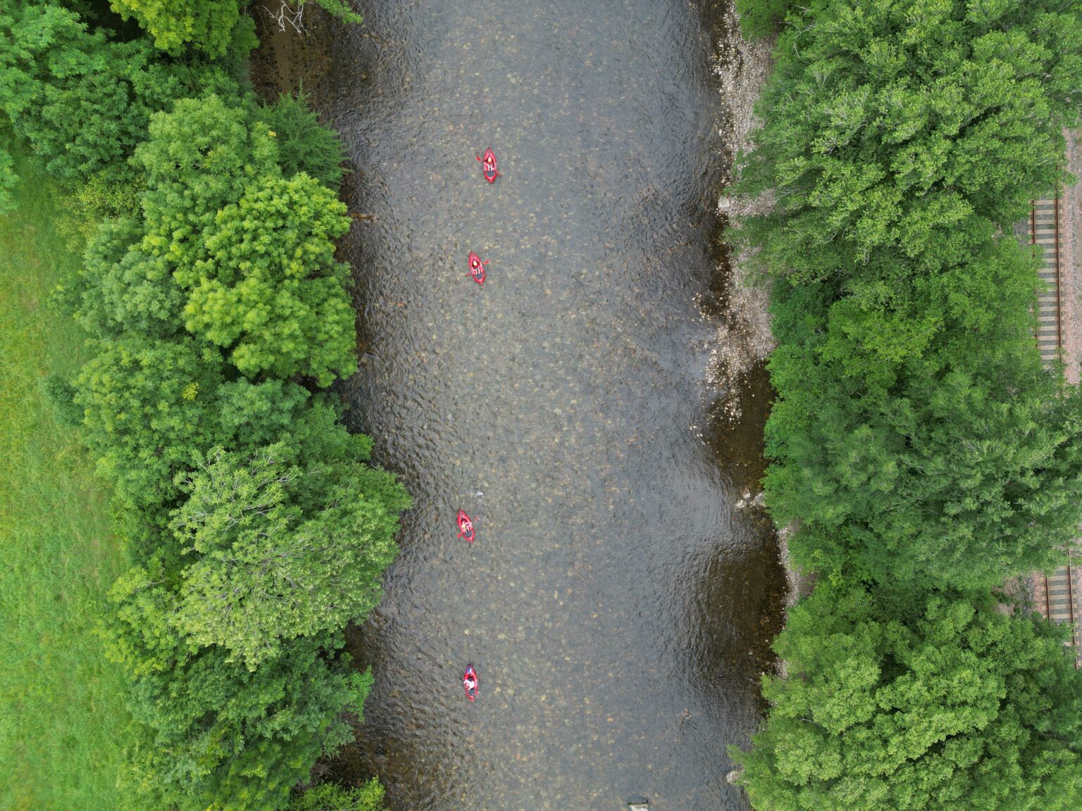 Vue drone de packrafts sur un gave bordé d'arbres