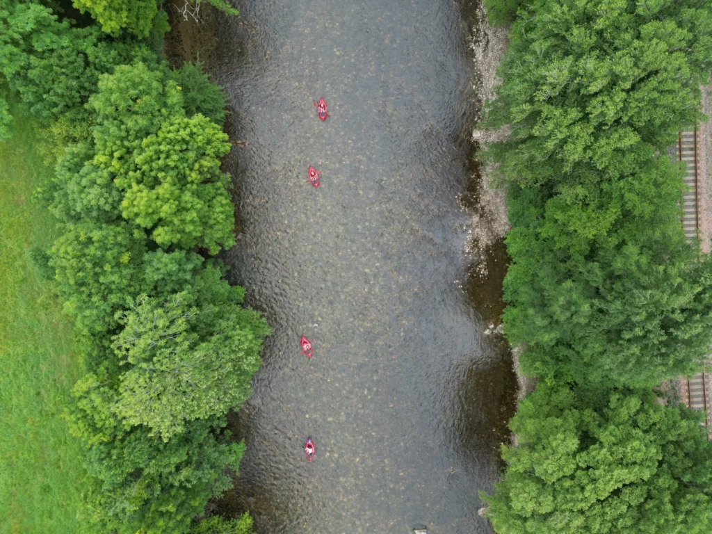 Vue aérienne de packrafts descendant une rivière bordée de forêt